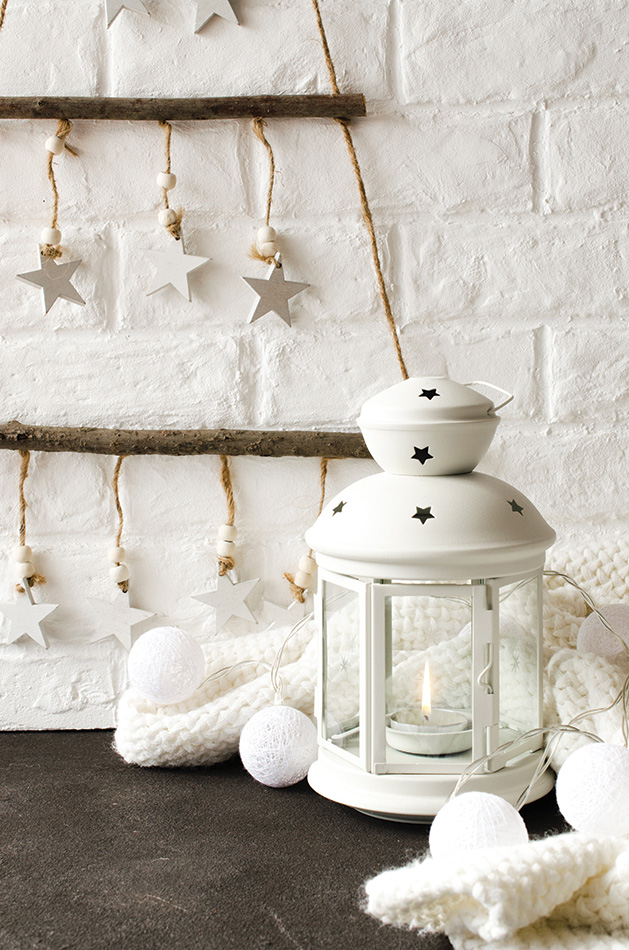 Scandinavian cozy home decor. Wooden stylish Christmas tree in scandinavian style against the background a white brick wall. White lantern, scarf and Christmas garland.
