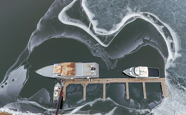 Boats surrounded by ice on the water on the St. Croix River at the Hudson Dike
