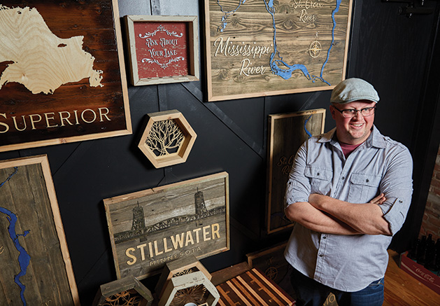 Tom Velure stands before some of his custom wood lake maps at Smith + Trade Mercantile.