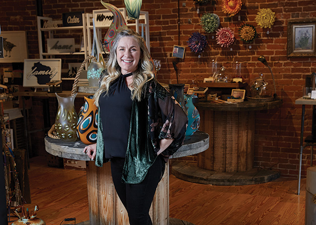Glass blower Marlo Cronquist stands before some of her works at Smith + Trade Mercantile.