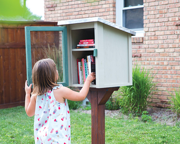 A little girl looks at the books in a Little Free Library.