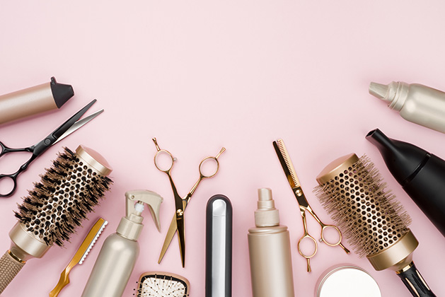 A row of various beauty products on a pink background.