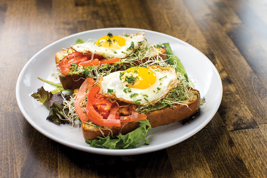 The Avocado Toast comes adorned with sprouts and fresh tomato—and a fried egg makes a delicious add-on.