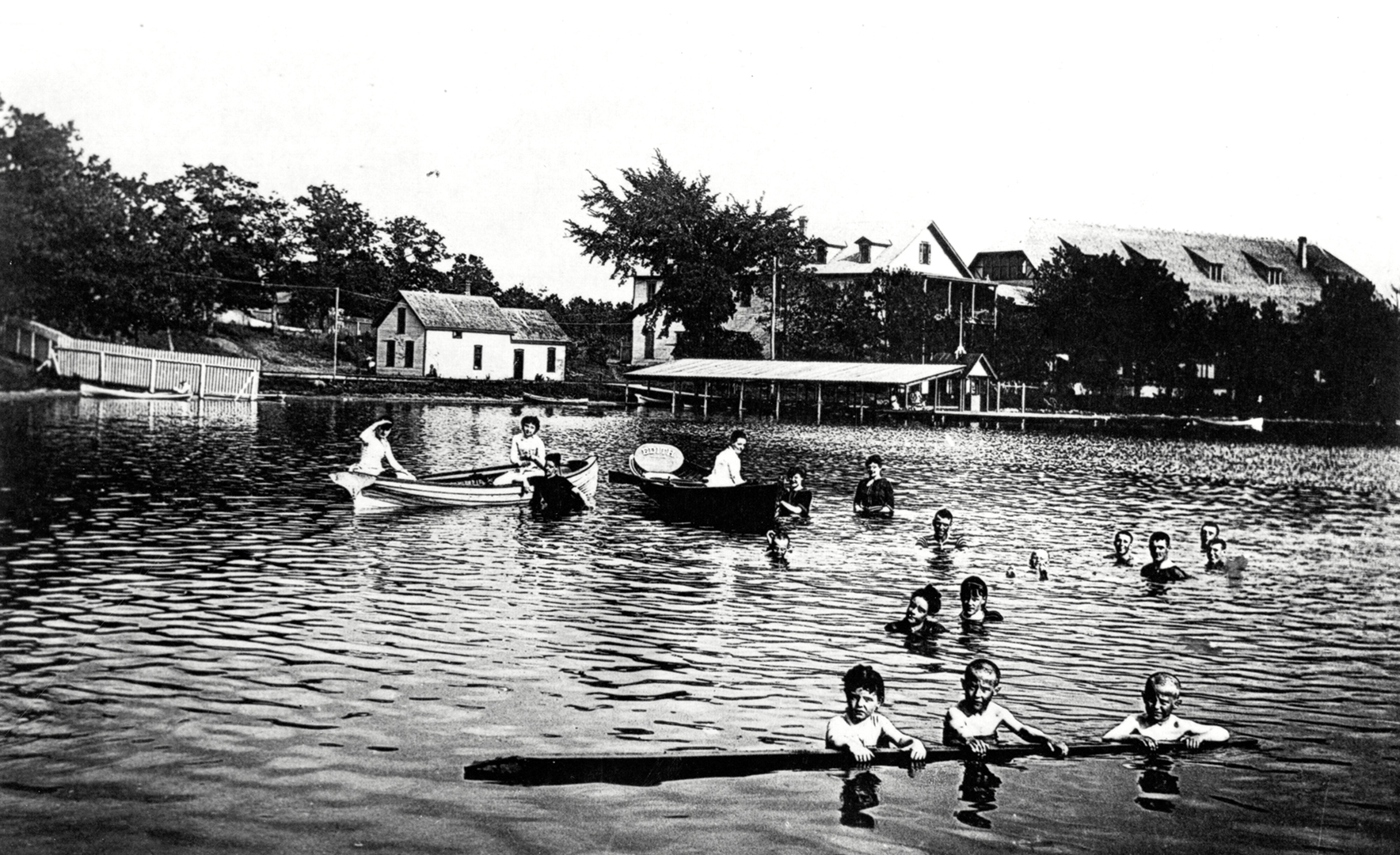Swimmers at Elmo Park with Elmo Park with resort buildings and boat docks in the background.
