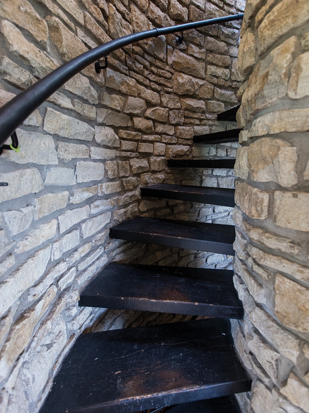 First floor: From the entrance of Greg Elsner and Kadie Fredell’s Taylors Falls home to the top floor, a vertical span of windows brings in light and natural views. Along with the primary bedroom and bathroom on the ground floor, there’s also the home’s centerpiece: a spiral staircase, robed in local stone, that wraps around a chimney. If you head down, you’ll find the children’s bedroom/playroom with its own bay of windows.
