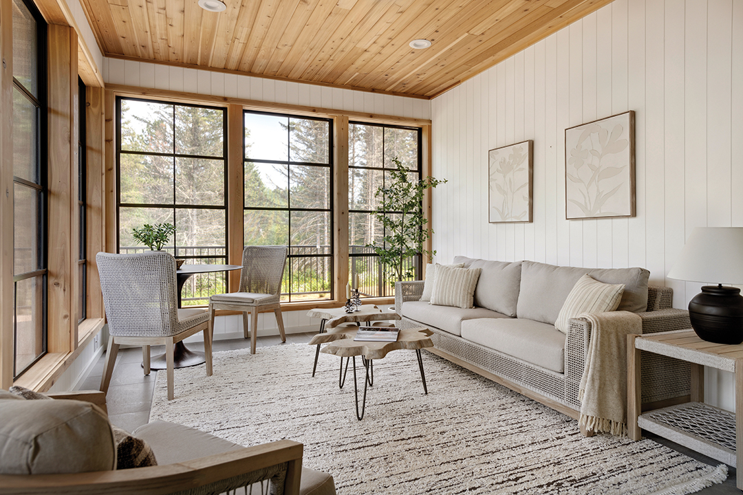 The screened porch includes an Eze-Breeze window system, allowing paneled vinyl windows to stack and shift to make the most of the weather in all seasons. The space’s furnishings, including a bistro table and chairs, feature woven rope detailing. Organically shaped wood nesting tables add a fun element to the room. “It’s a great place to have coffee in the morning. The sun comes through, and you look out at the river flowing … I could stay all day,” Heidi Hove says.