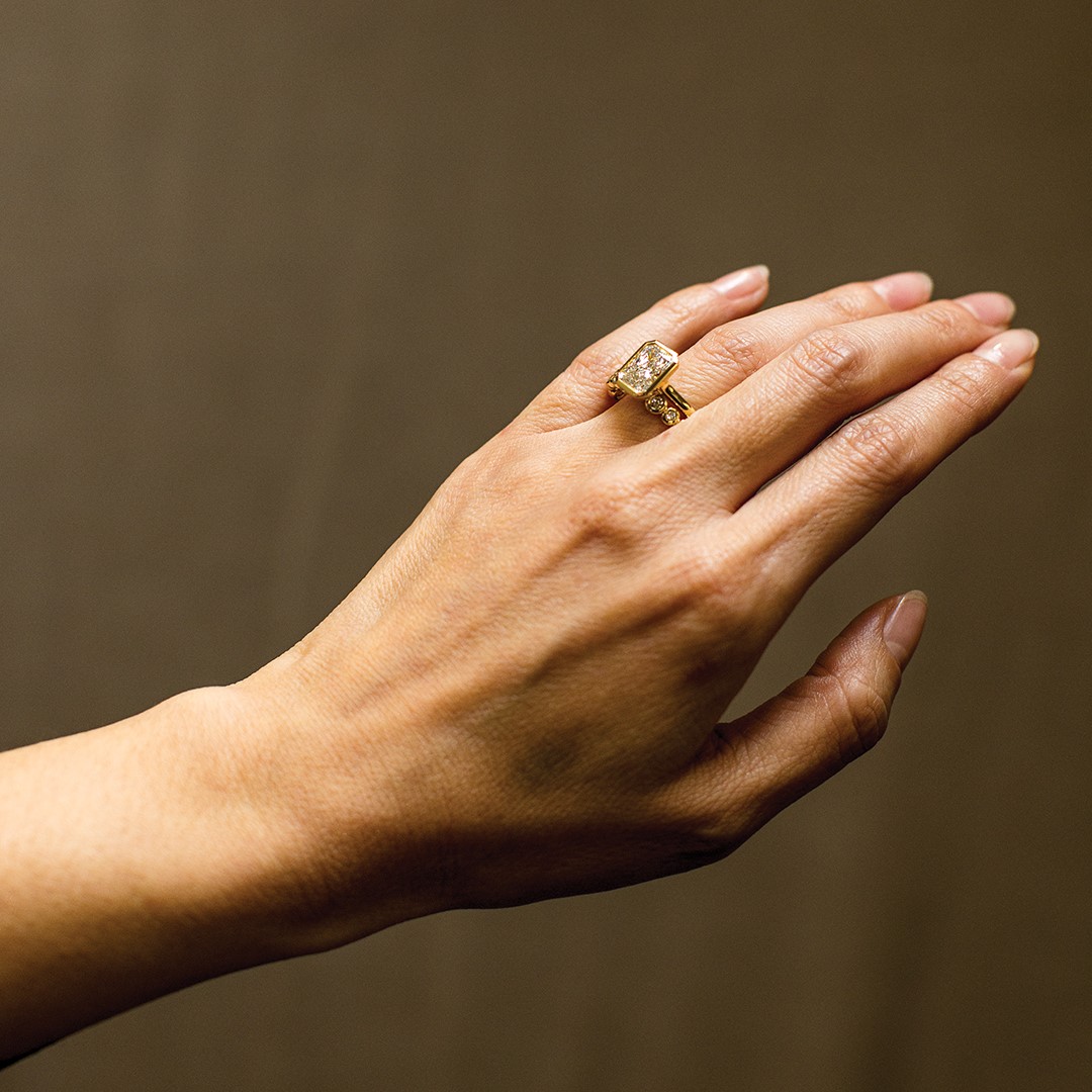Kristen Iburg Meyer often works with yellow gold in her custom engagement ring designs. This radiant cut diamont solitaire ring and wedding band with round bezel-set diamonds highlights the distinctive material.