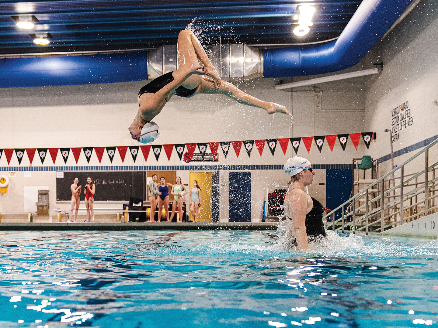Captain Hailey Schmit is launched into the air during practice with the help of six fellow senior swimmers, including Hanna Wiese, pictured.