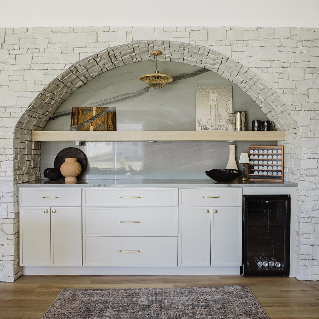 The bar features a quartz slab for the countertop and arched backsplash and is framed by contrasting flagstone.
