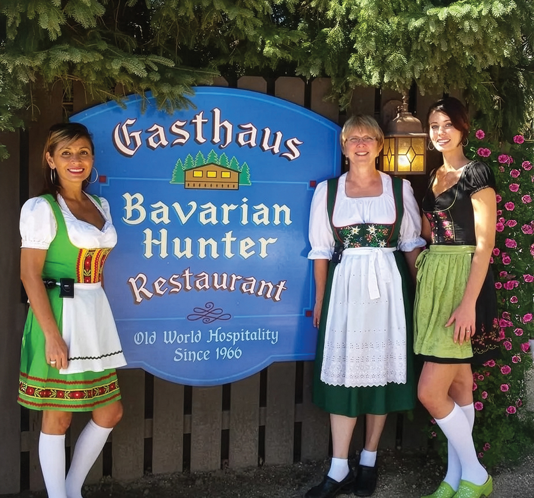 Women posing in front of the Gasthaus Bavarian Hunter sign
