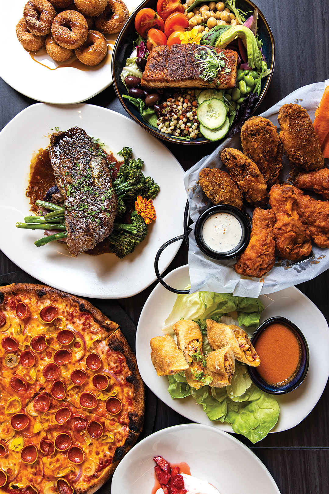 The menu at The Grounds is as vibrant as it is intentional. Crowd favorites, as pictured, include the Mini Donuts, Protein Bowl with Salmon, New York Strip Steak, Chicken Wings, Thai Egg Rolls, Lobo Pizza and Pavlova.