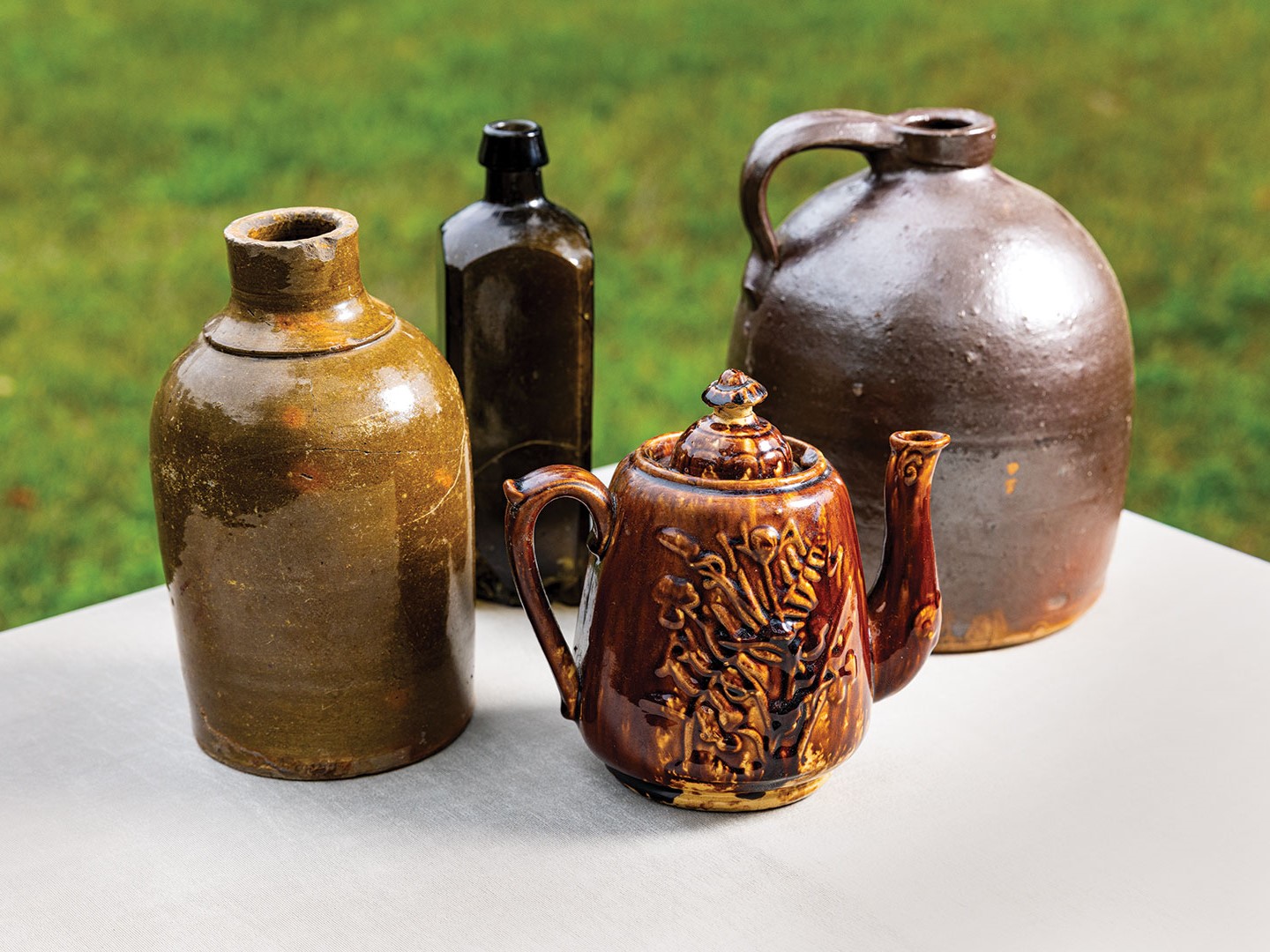 Pioneer Archeology finds (from left to right) include a Galena Illinois Pottery storage vessel (c. 1850) a bitters bottle (c. 1855), a Rockingham tea pot (c. 1860) and a 2 gallon jug with Albany slip brown glaze found (c. 1855).