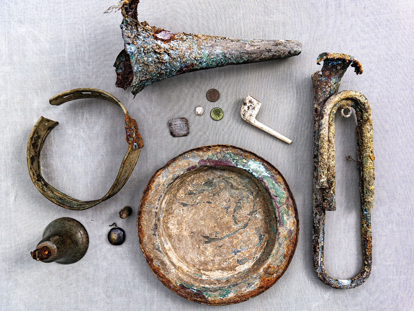 Metal detecting allows the Pioneer Archeology team to discover a wide variety of historic artifacts, including (pictured) bugels, a Civil War-issued plate, a clay penny pipe and a pipe windcap dating to the late 1700s.