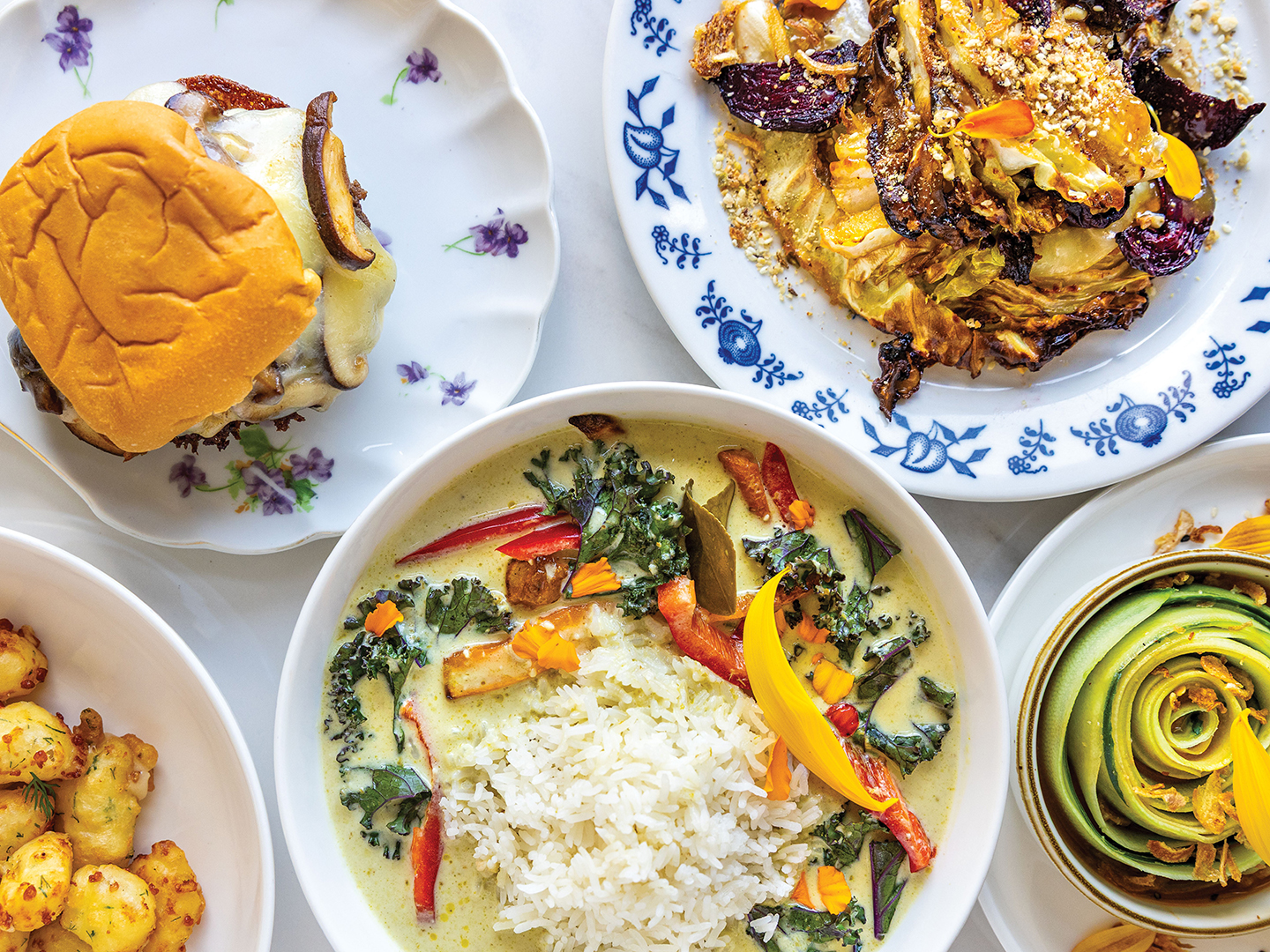 Clockwise from left: Cucumber Salad, Maple Miso Roasted Cabbage, Mushroom Burger, Cheese Curds and Thai Green Curry With Veggies.